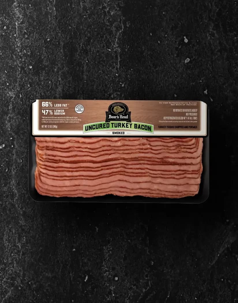 A aerial view of a package of the Boar's Head® Uncured Turkey Bacon sits on a graphite colored background.