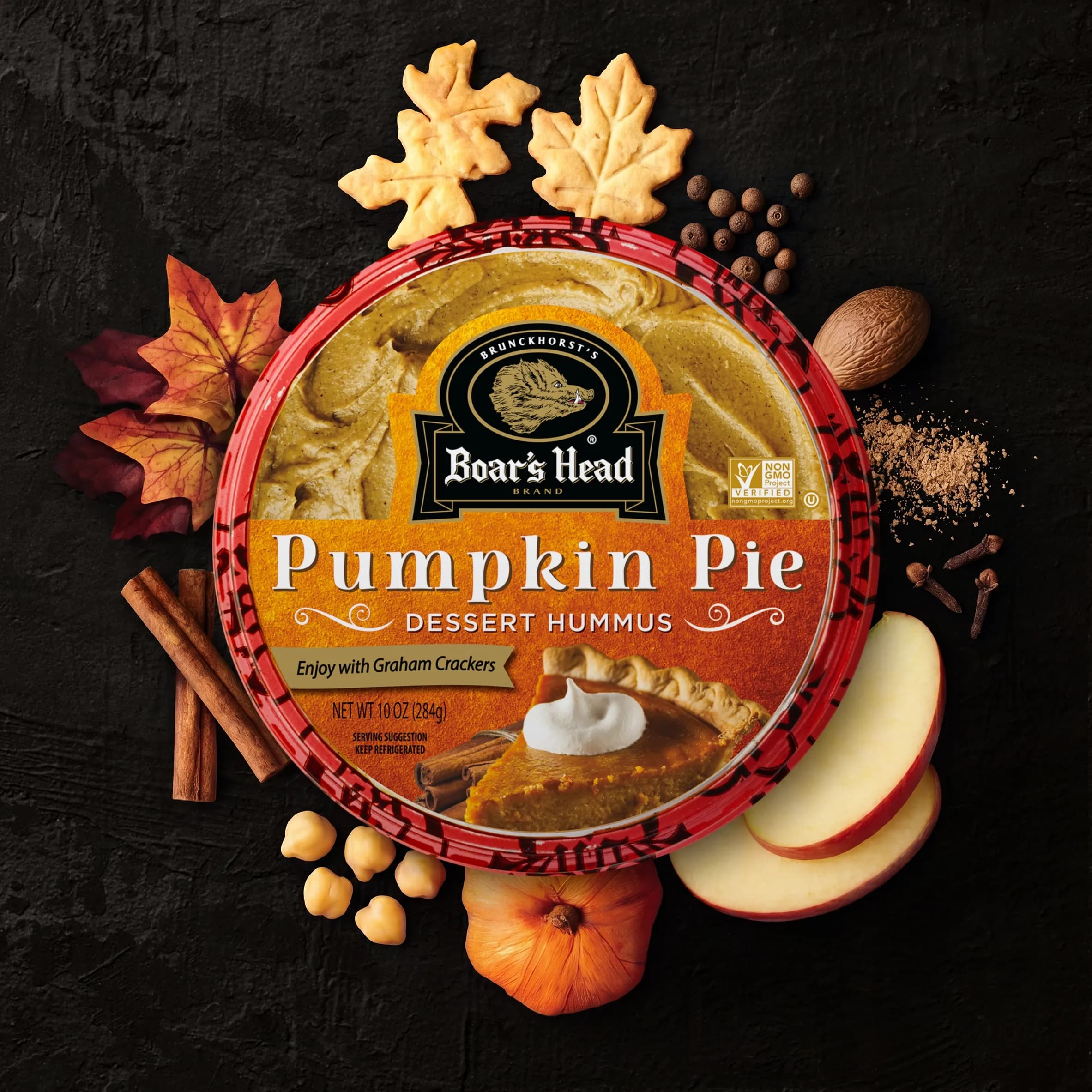 An aerial view of the Boar's Head® Pumpkin Pie Hummus, surrounded by fall leaves, pumpkin, cinnamon sticks, and slices of apple.